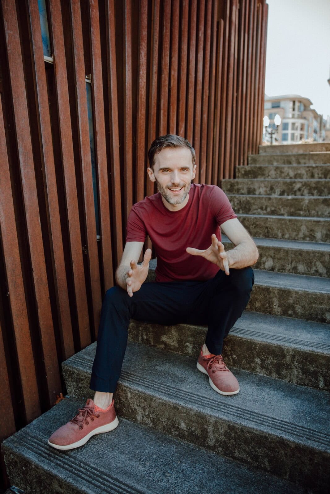 Michael sitting on steps holding hands out toward viewer